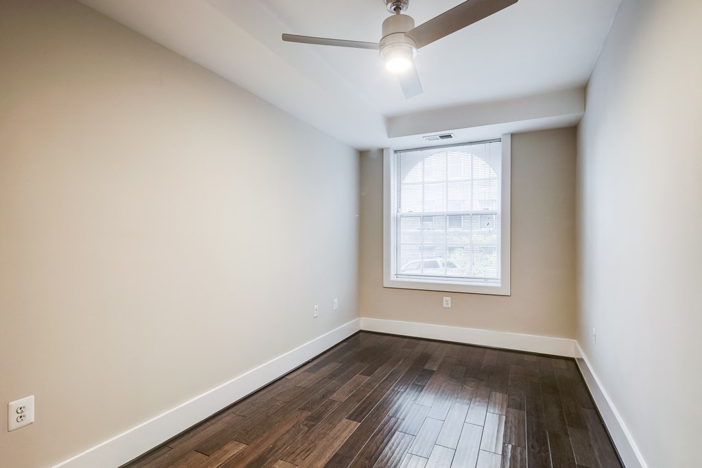 an empty living room with hard wood flooring and a window