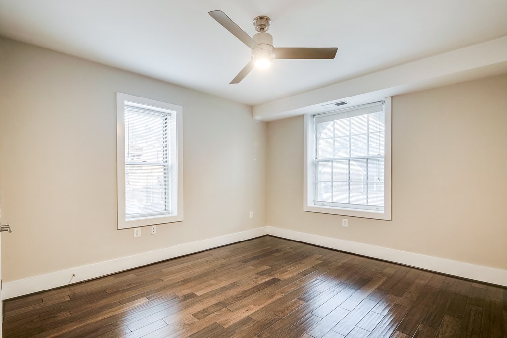 an empty living room with wood floors and a ceiling fan