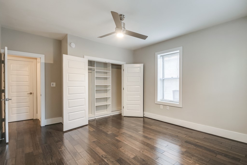 an empty living room with a closet and a ceiling fan