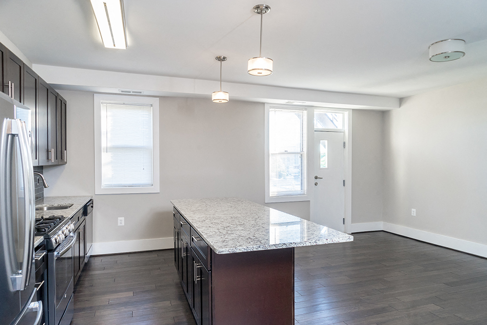 an empty kitchen with stainless steel appliances and a marble counter top