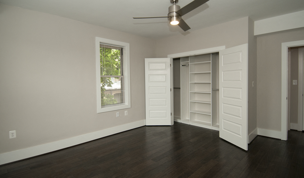 an empty living room with hard wood floors and a ceiling fan