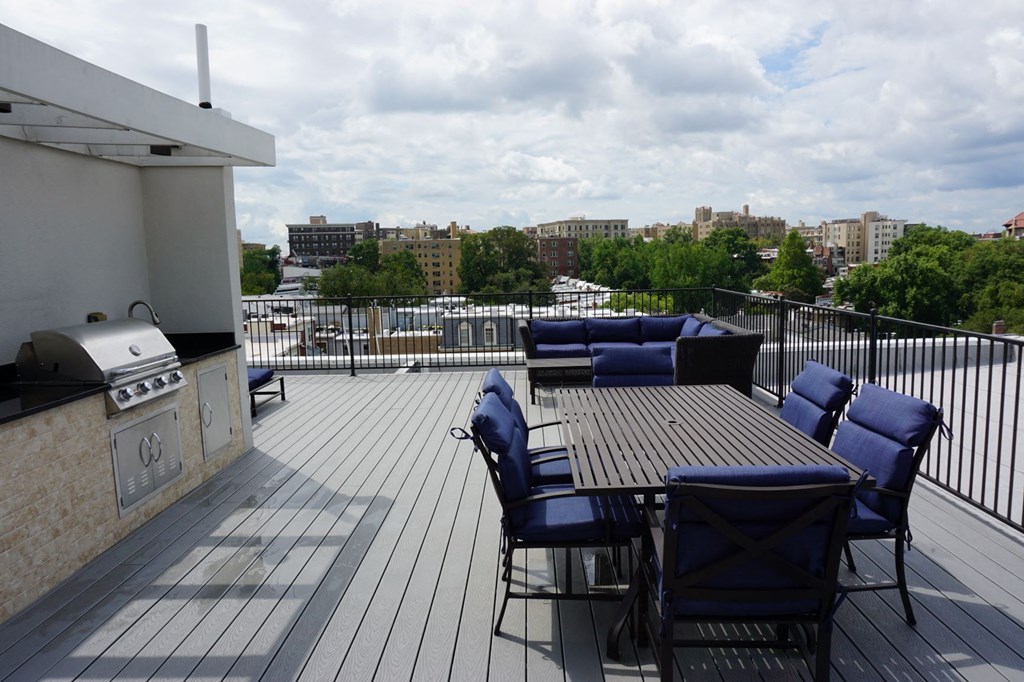 a deck with a table and chairs and a grill on a roof