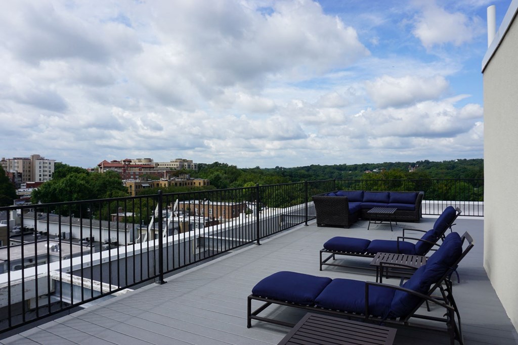 a balcony with blue couches and chairs and a cloudy sky