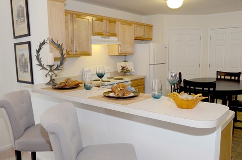A kitchen with a white counter and a grey chair.