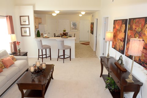 A living room with a couch, coffee table, and bar stools.