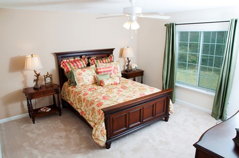 A bedroom with a large bed and a ceiling fan.