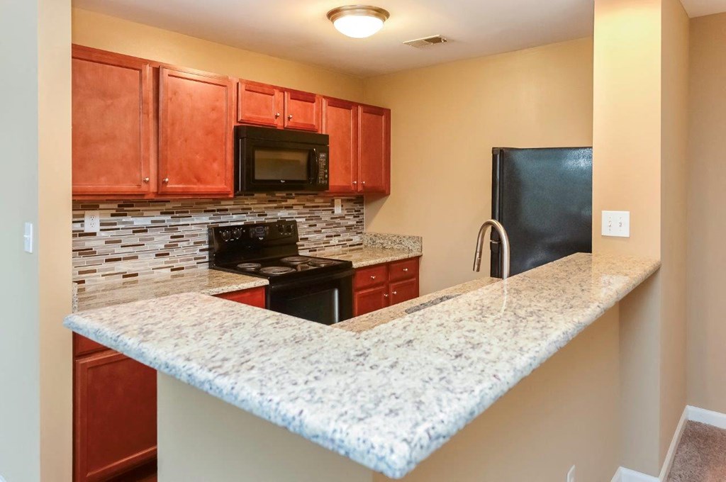 a kitchen with a granite counter top and a black refrigerator