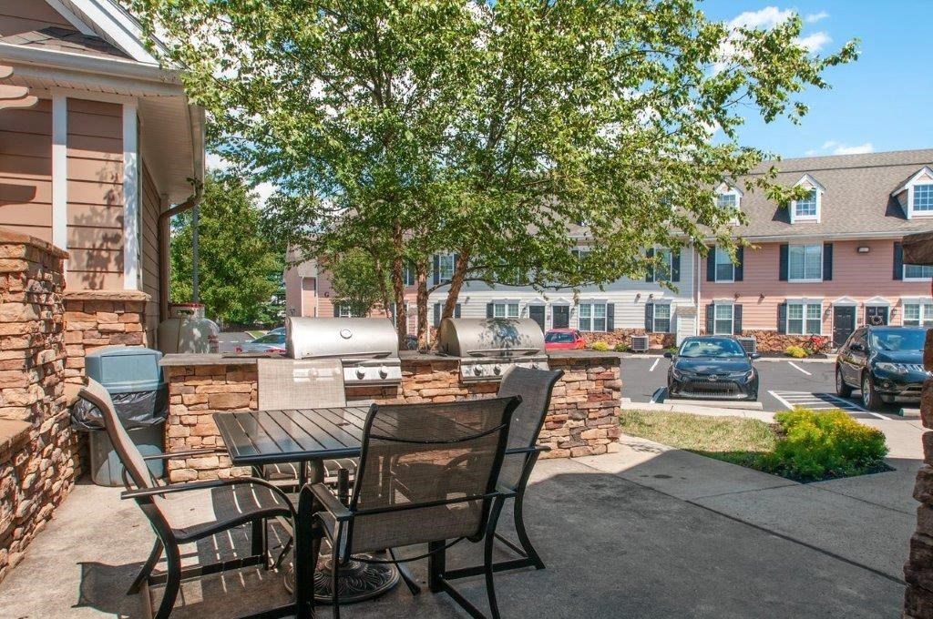 a patio with a table and chairs and a grill