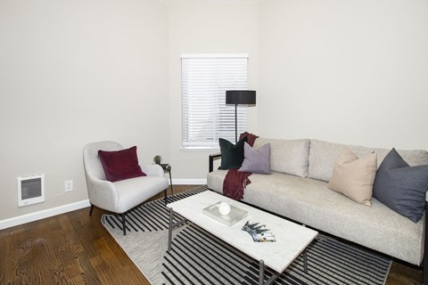 A living room with a white chair, a white coffee table, and a beige couch with pillows.