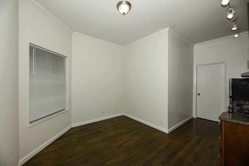 A room with a wooden floor and a window with blinds.