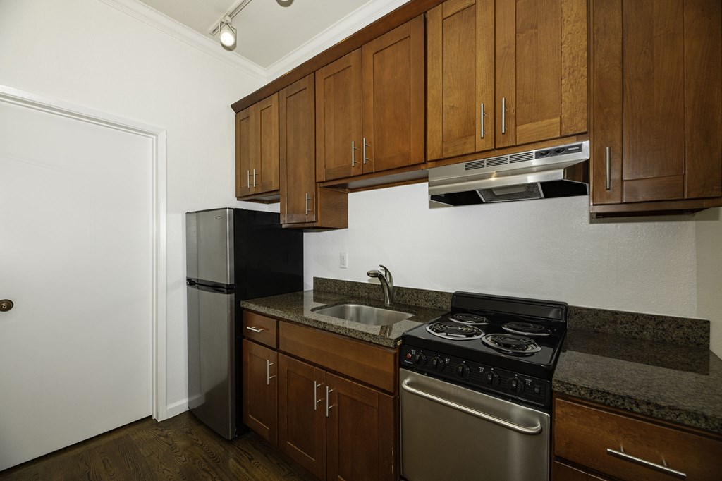 A kitchen with a stove, sink, and cabinets.