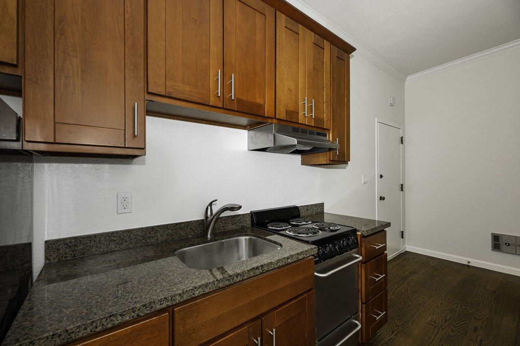 A kitchen with a stove, sink and cabinets.
