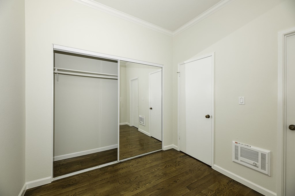 A white closet with a mirrored door and a white door.