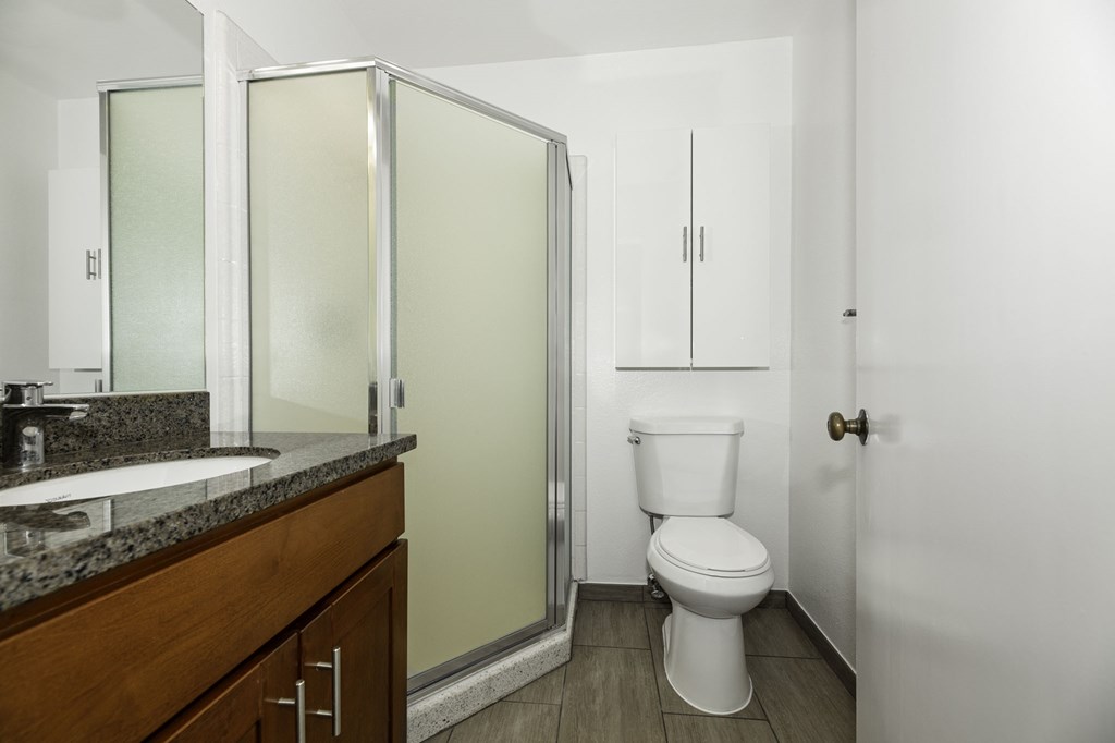 A white toilet sits in a bathroom next to a sink and a glass shower door.