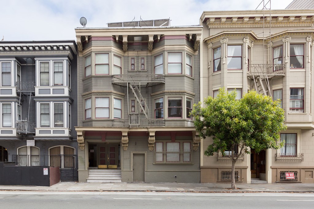 A row of three apartment buildings with balconies and doors.