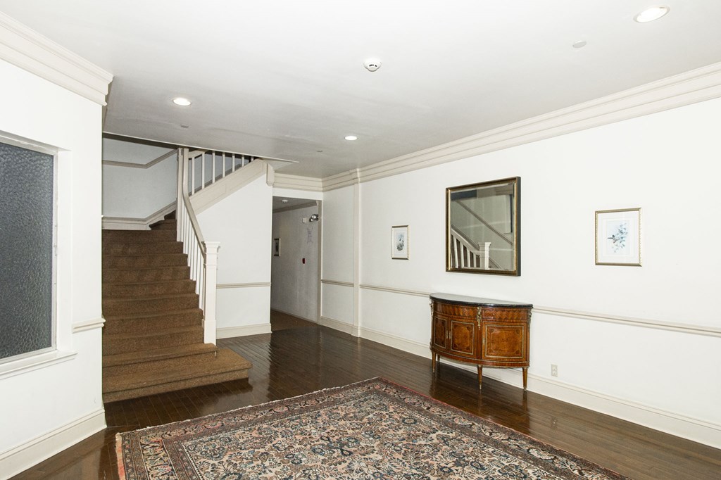 A hallway with a rug on the floor and a wooden cabinet.
