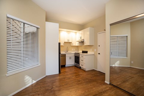 A kitchen with white cabinets and a wooden floor.