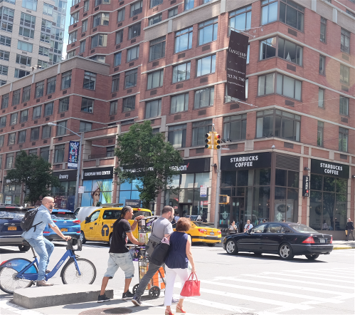 a group of people crossing the street at a crosswalk on a busy city street
