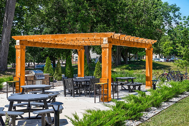 a group of tables and chairs under a wooden canopy