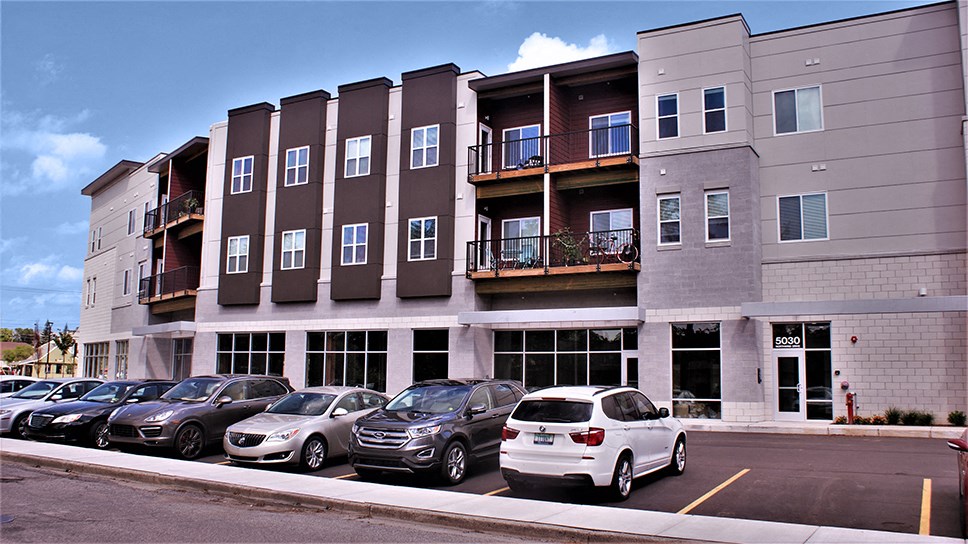 a parking lot with cars in front of an apartment building