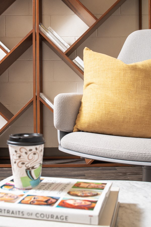 a chair with a pillow and a coffee cup on a table