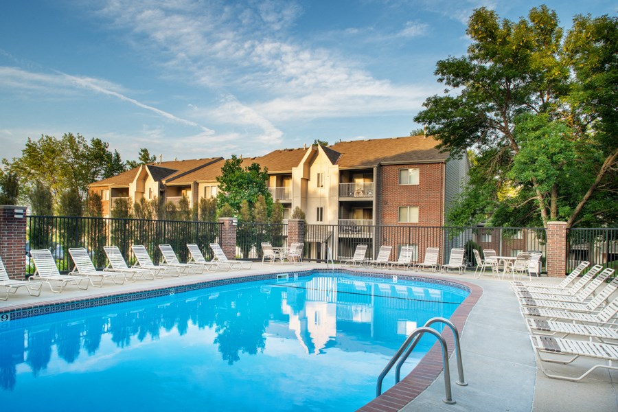 a swimming pool with chairs and a building in the background