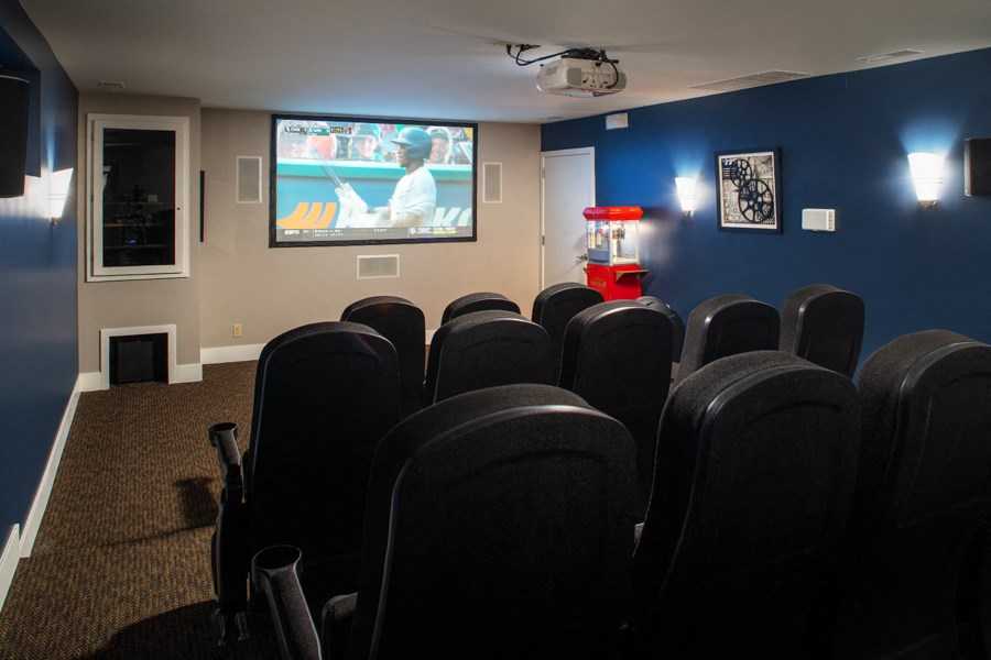 a theater room with blue chairs and a tv screen