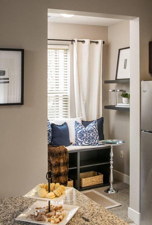a small dining room with a table and a chair and a window with white curtains