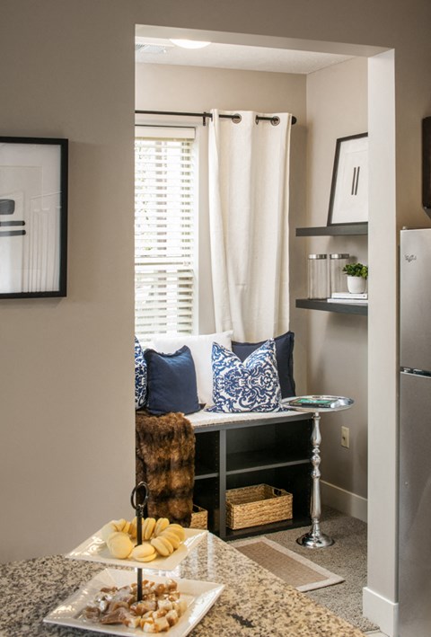 a small dining room with a table and a chair and a window with white curtains