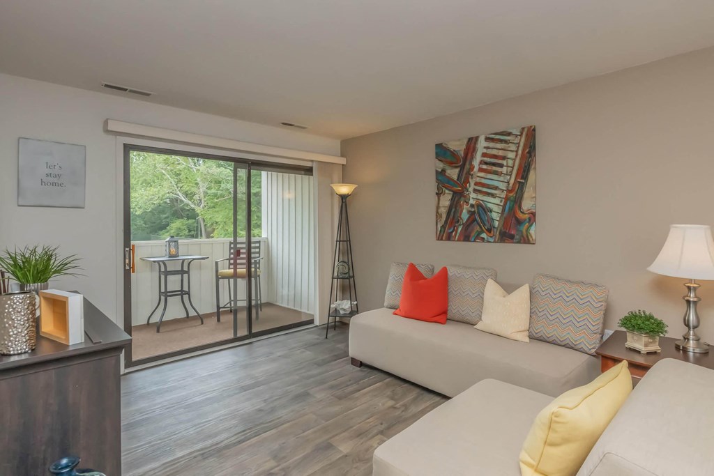 a living room with white furniture and a sliding glass door to a patio