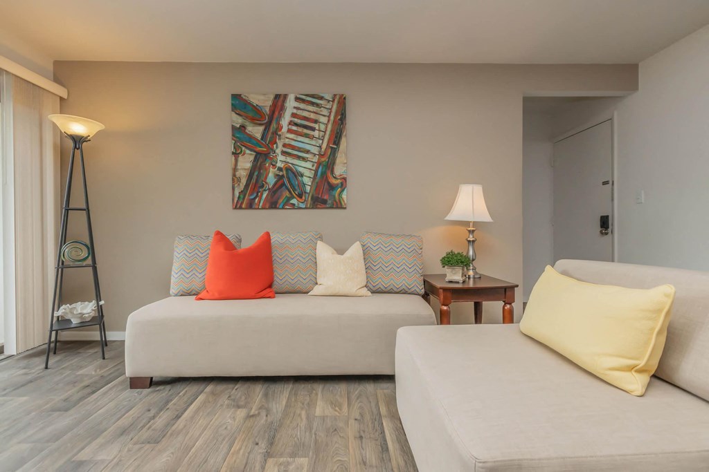 a living room with white furniture and a painting on the wall