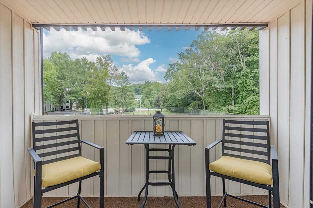 a balcony with two chairs and a table and a view of trees