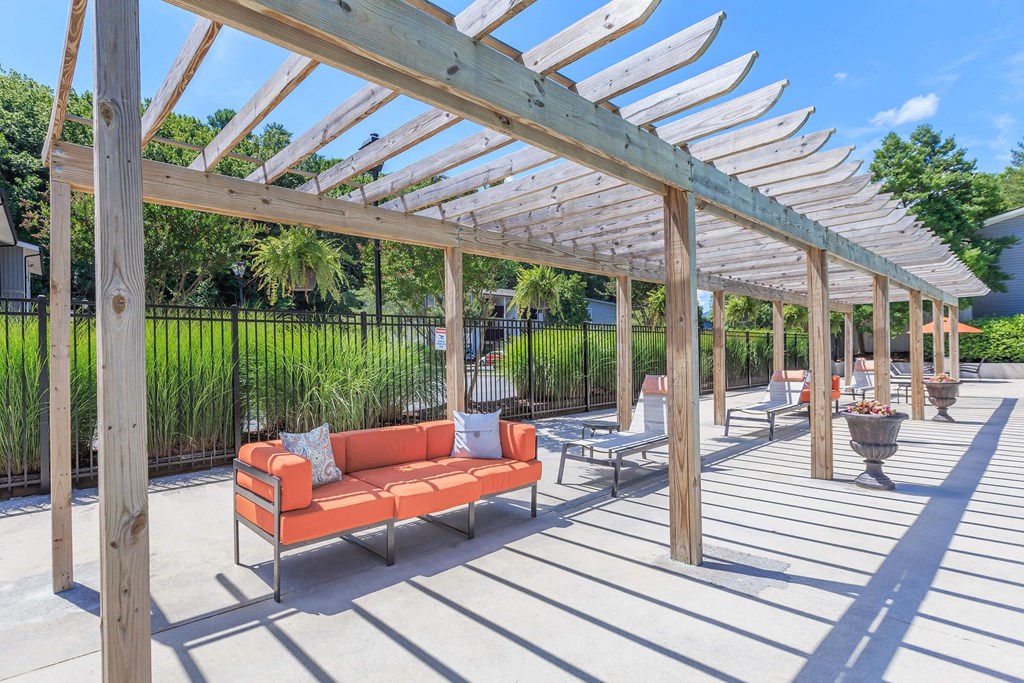 a covered patio with a couch and chairs under a wooden pergola