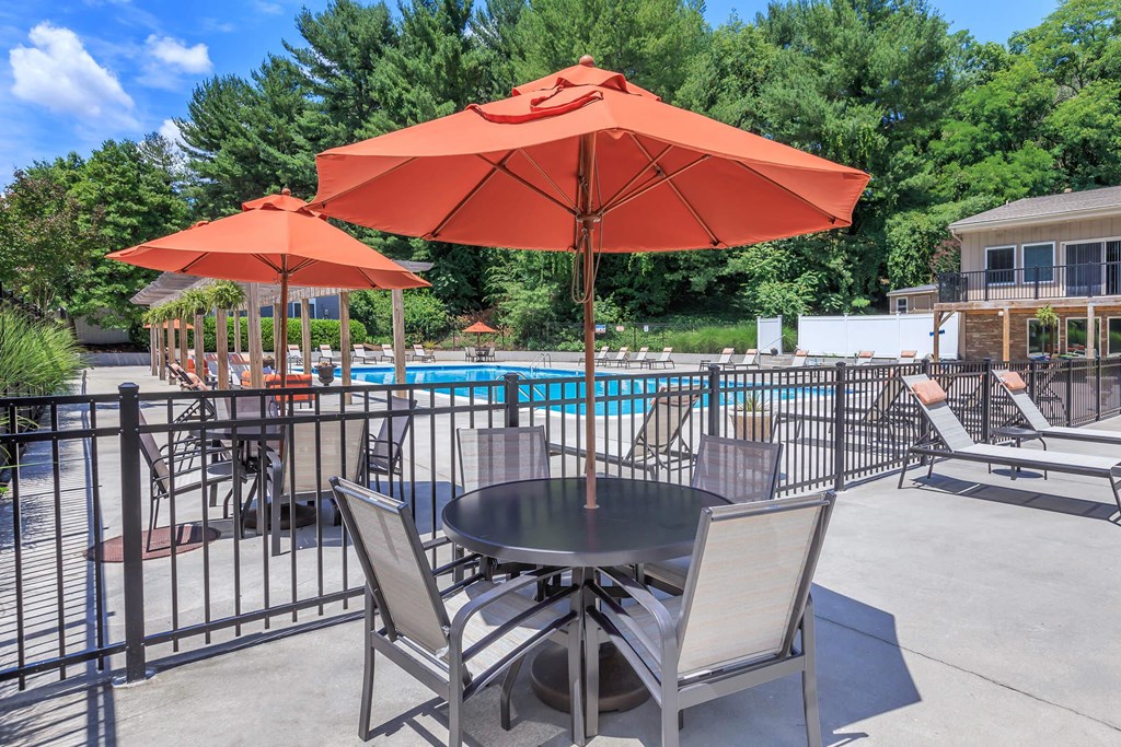 a patio with tables and umbrellas next to a pool
