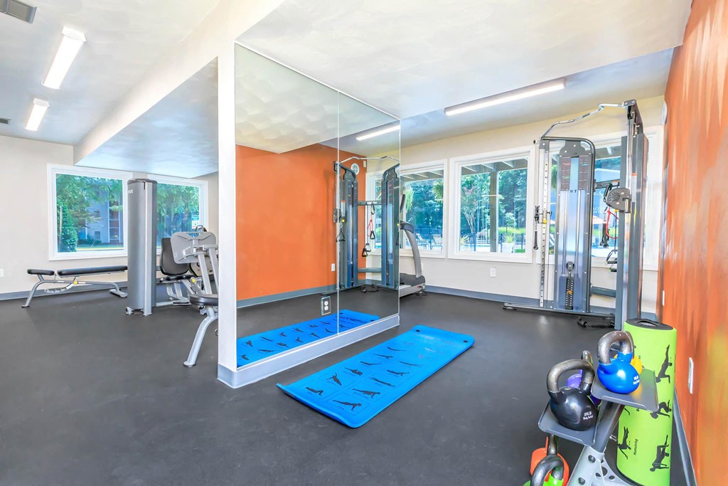 a gym with exercise equipment and yoga mats on the floor