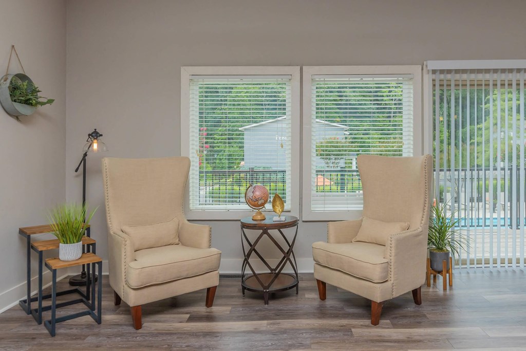 a living room with two chairs and two windows