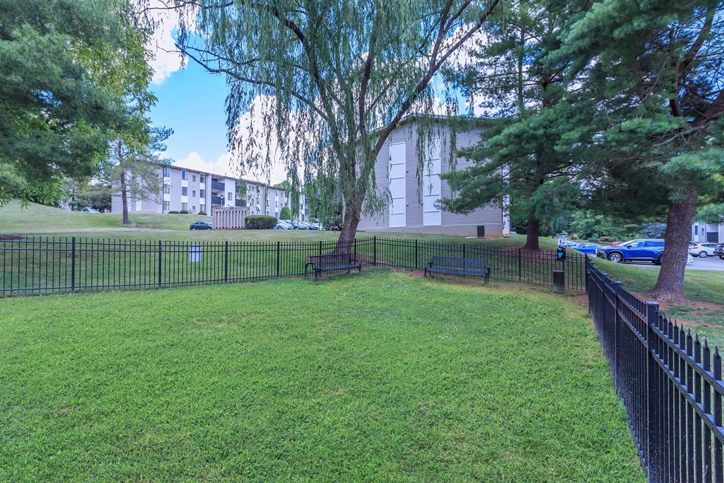 a yard with benches and a fence in front of a building