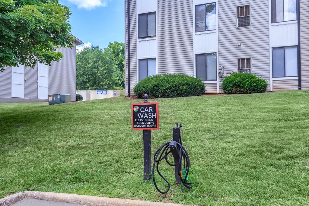 a car wash sign in the grass in front of an apartment building