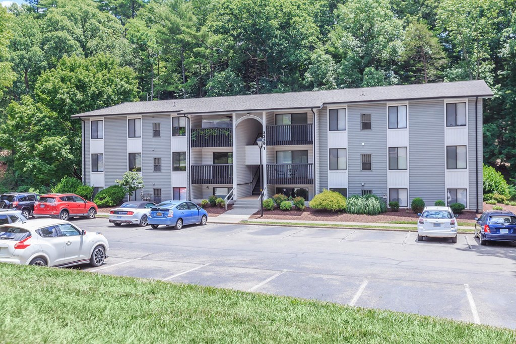 an apartment building with cars parked in a parking lot