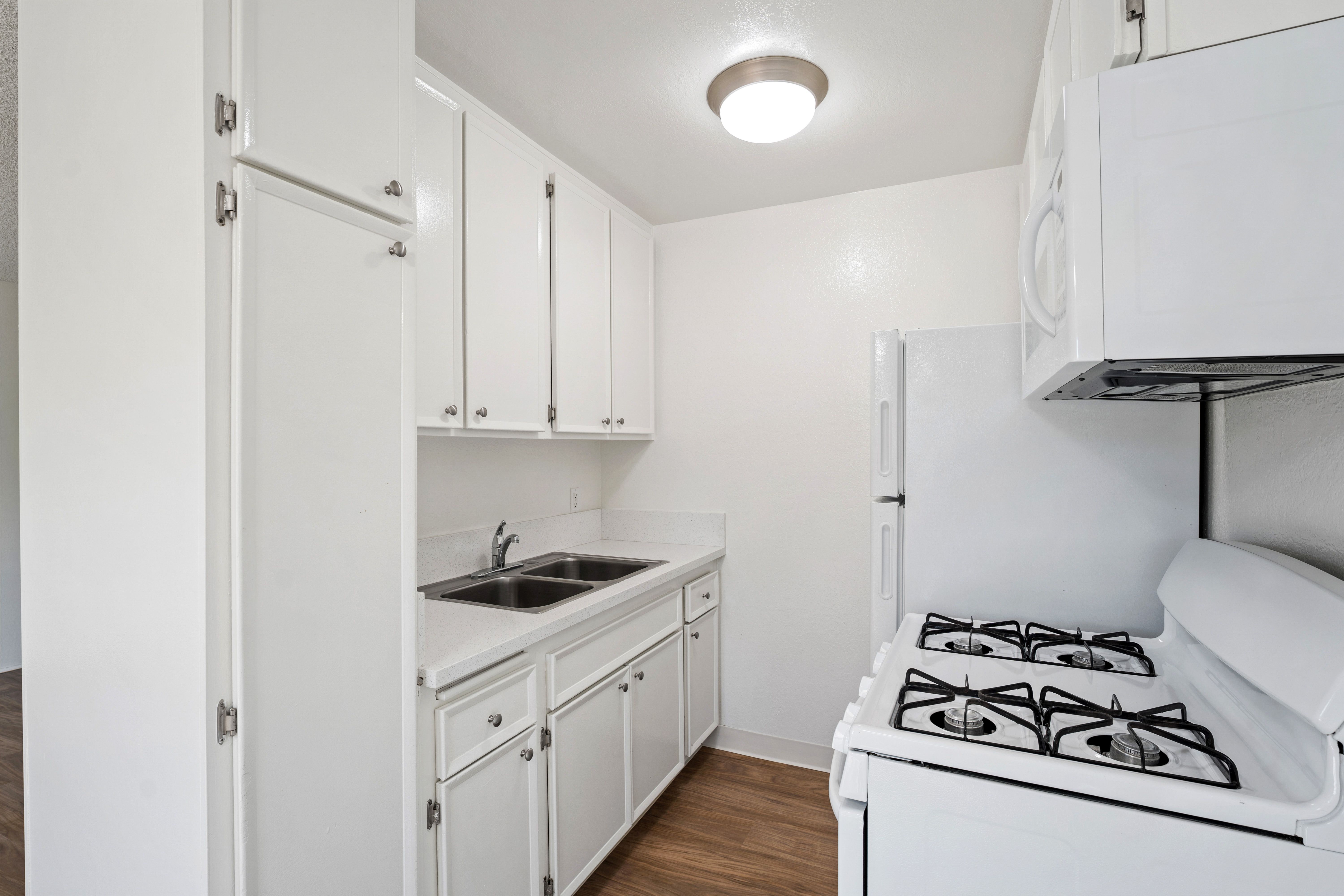 A white kitchen with a stove and sink.