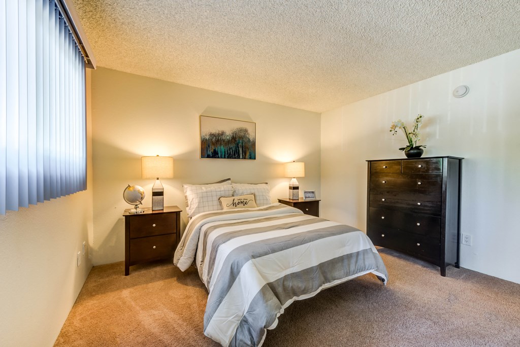 a bedroom with a bed and a dresser and a window