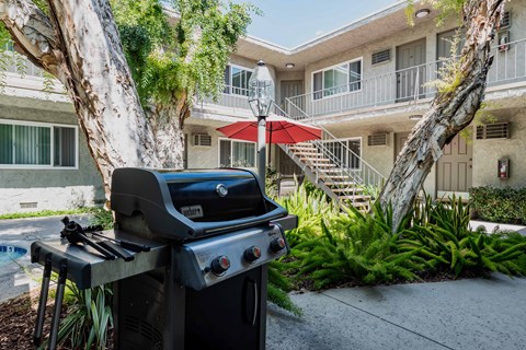 a grill in front of an apartment building with a patio
