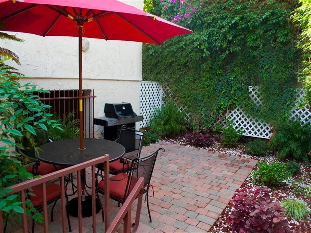 a patio with a red umbrella and a table and chairs