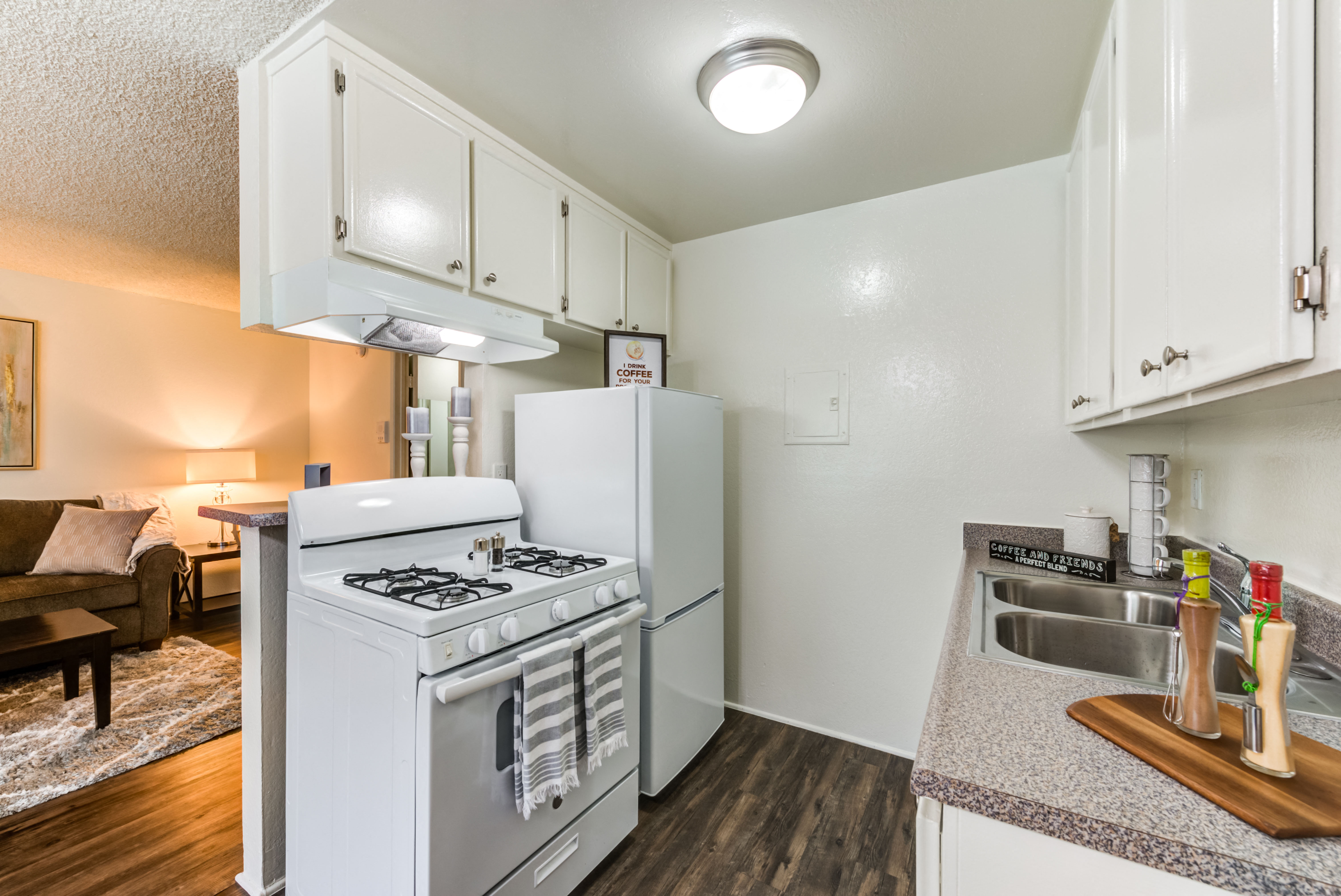 Open concept kitchen with gas range, fridge, and plank flooring at the Promenade Apartment in Van Nuys, CA