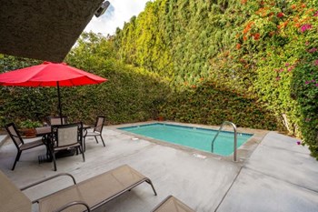 The pool at the Ridgeview Apartments in Northridge surrounded by beautifully manicured trees with patio seating and loungers to relax on a warm sunny day - Photo Gallery 8