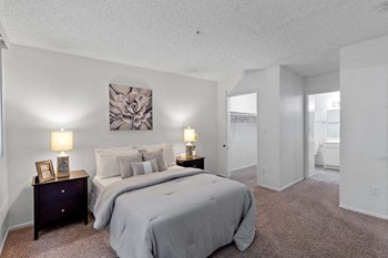 Spacious primary bedroom with walk-in closet and an attached bathroom. The bedroom and the walk-in closet flooring is carpeted, which makes it a perfectly cozy space to relax. - Photo Gallery 7