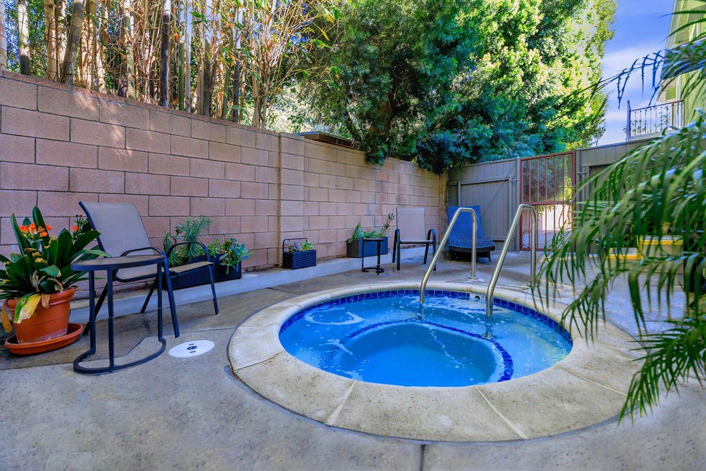a small pool in the backyard of a home with a hot tub