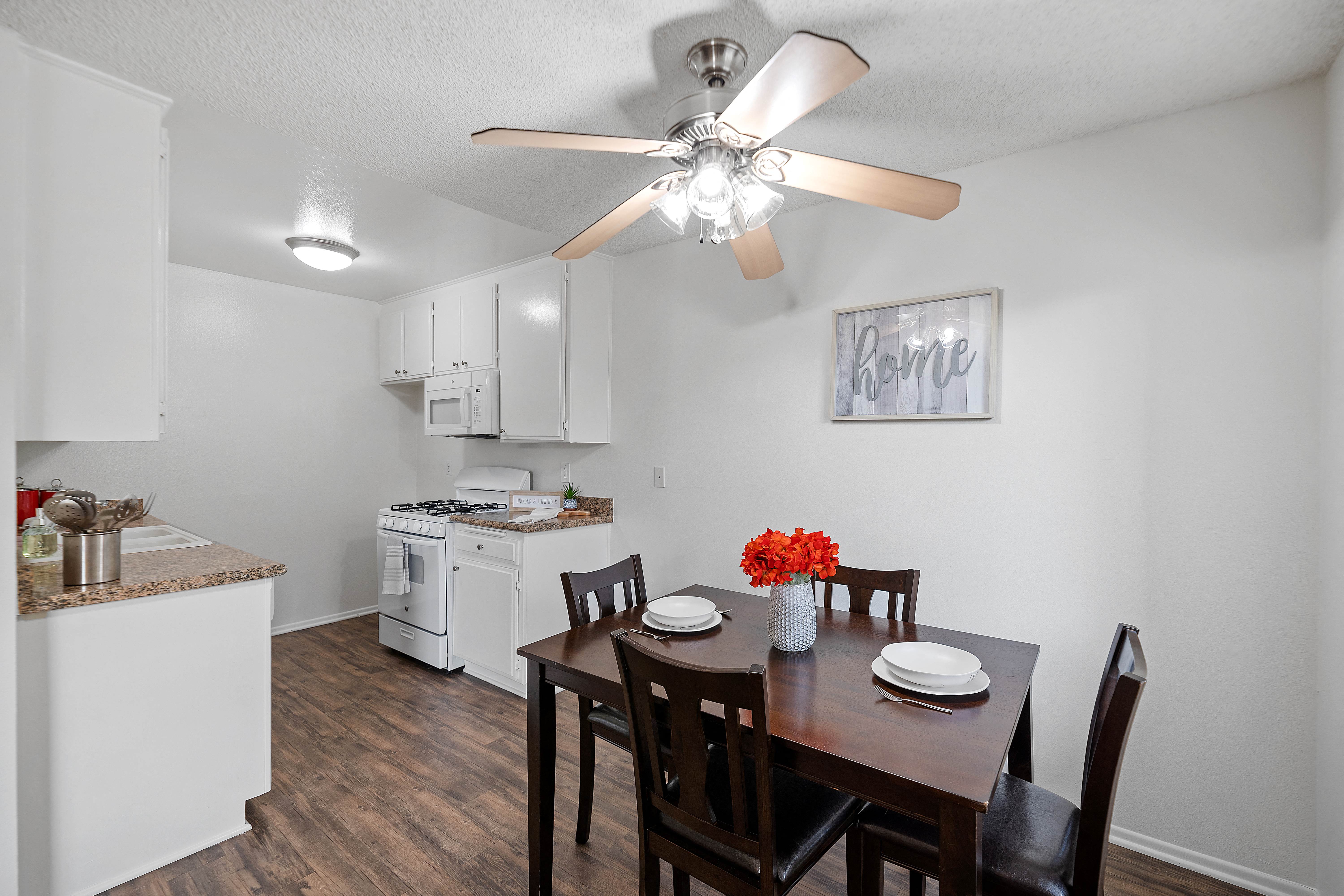 a dining room and kitchen with a table and chairs and a ceiling fan