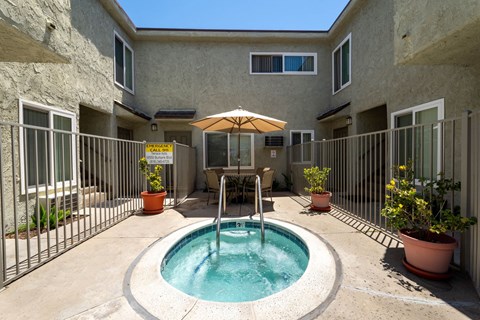 a small pool is in the middle of a patio with a fence and a building
