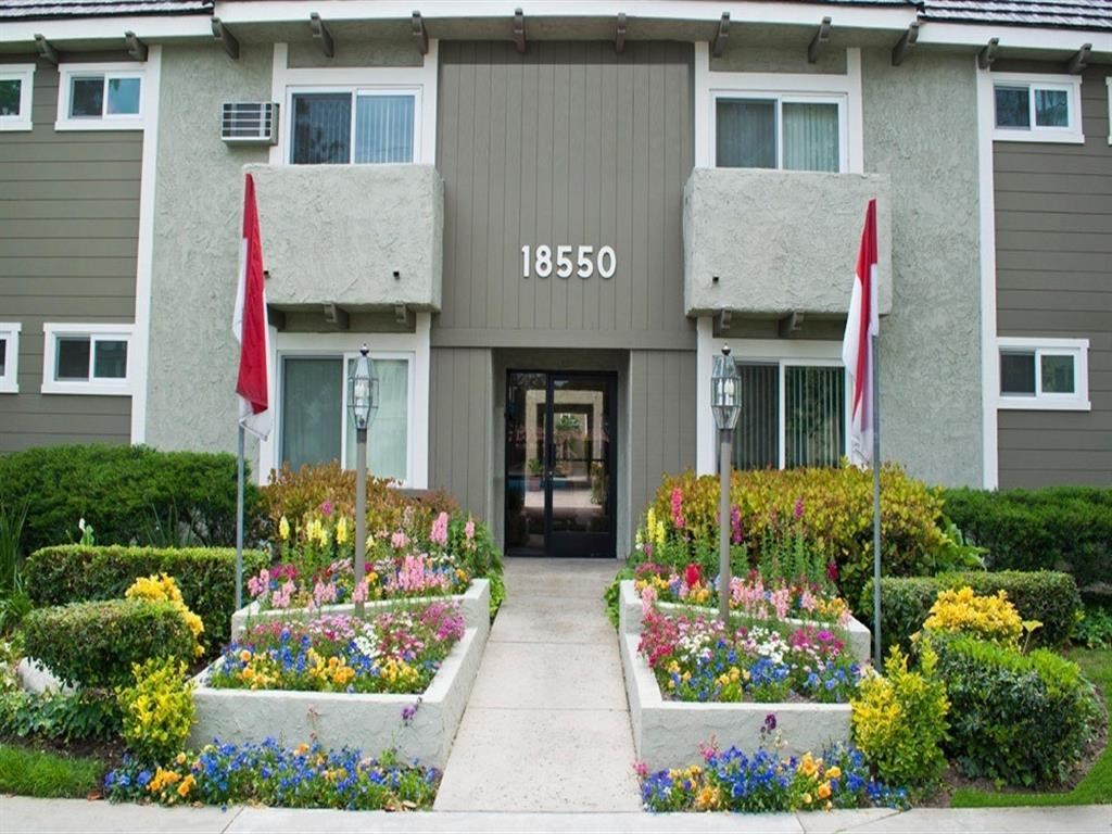 the front entrance of an apartment building with flower beds
